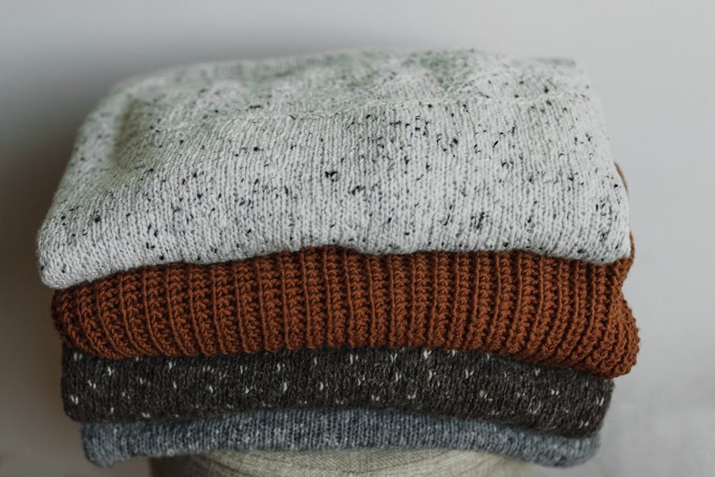 Close-up of folded cozy knit sweaters in neutral tones, perfect for autumn and winter fashion.
